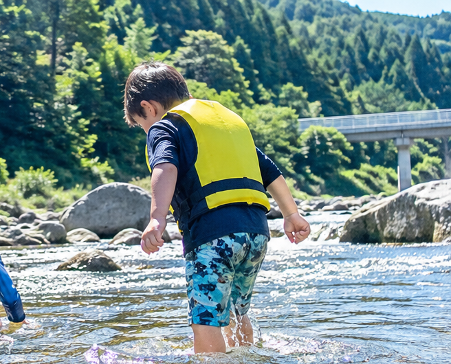 Children playing in a clear river in rural Japan during summer vacation.